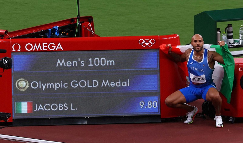 男子100メートル決勝を制し、国旗を持って喜ぶイタリアのラモントマルチェル・ヤコブス=国立競技場で2021年8月1日、宮武祐希撮影