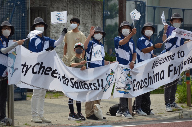 手旗を振って大会関係者を歓迎するボランティアら=神奈川県藤沢市で2021年7月31日午前8時36分、井口慎太郎撮影