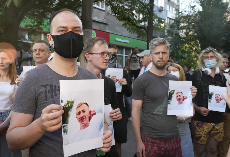 遺体で発見されたビタリー・シショフ氏の写真を掲げて、ウクライナのベラルーシ大使館の前で抗議活動をする人たち＝ウクライナの首都キエフで2021年8月3日、AP