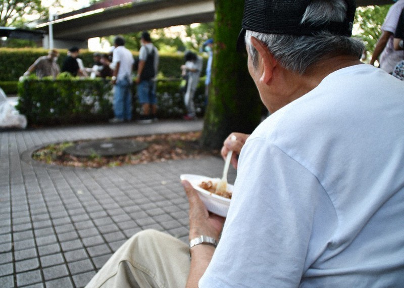 代々木公園の炊き出しには多くの人が集まる。この日はカレーが提供され、その場で空腹を満たしていた=東京都渋谷区で7月27日