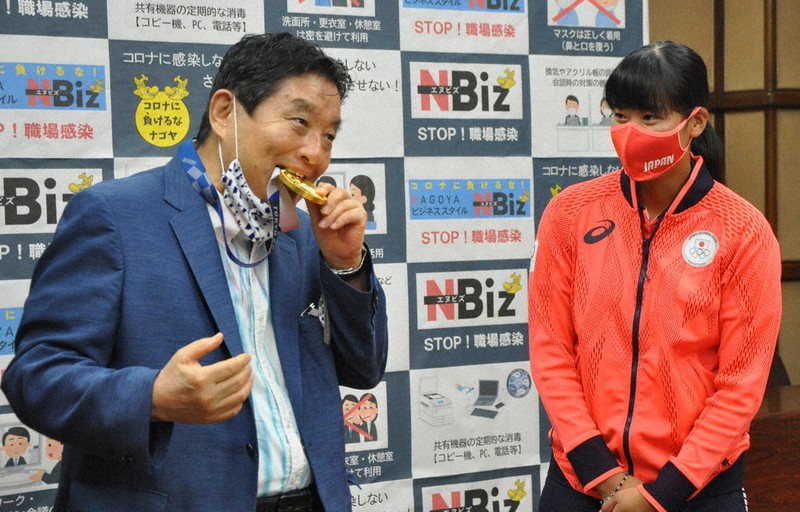 女子ソフトボールの後藤希友選手(右)の金メダルをかむ河村たかし名古屋市長=市役所で2021年8月4日、岡正勝撮影