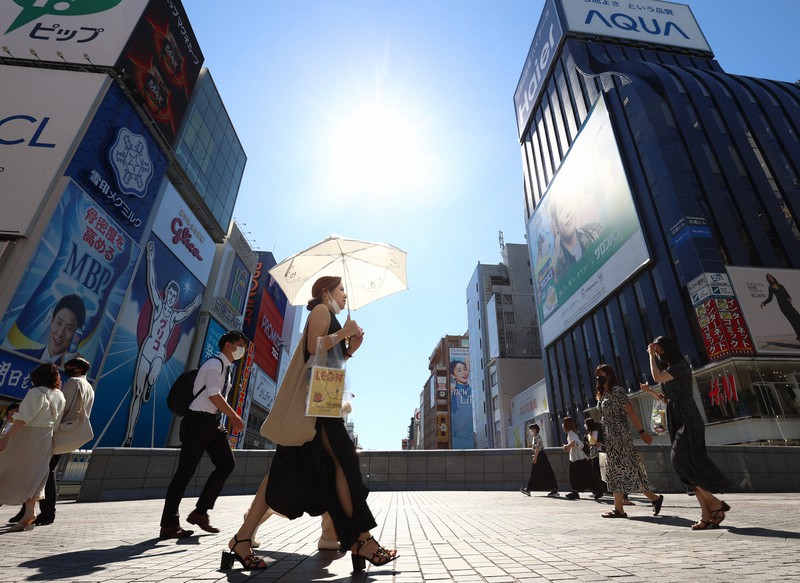 猛暑日を記録し、日傘をさして歩く人たち=大阪市中央区で2021年7月19日午後3時20分、猪飼健史撮影