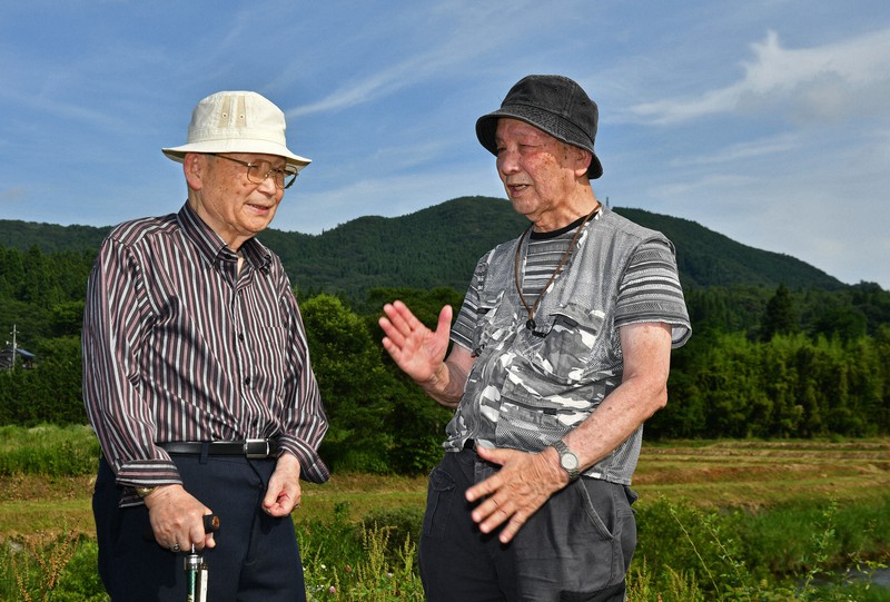 国民学校3年生の時に、黒い雨を浴びた集落で自身の半生を振り返る住田康雄さん(右)と同級生の河野博さん=広島県廿日市市で2021年7月24日、山田尚弘撮影