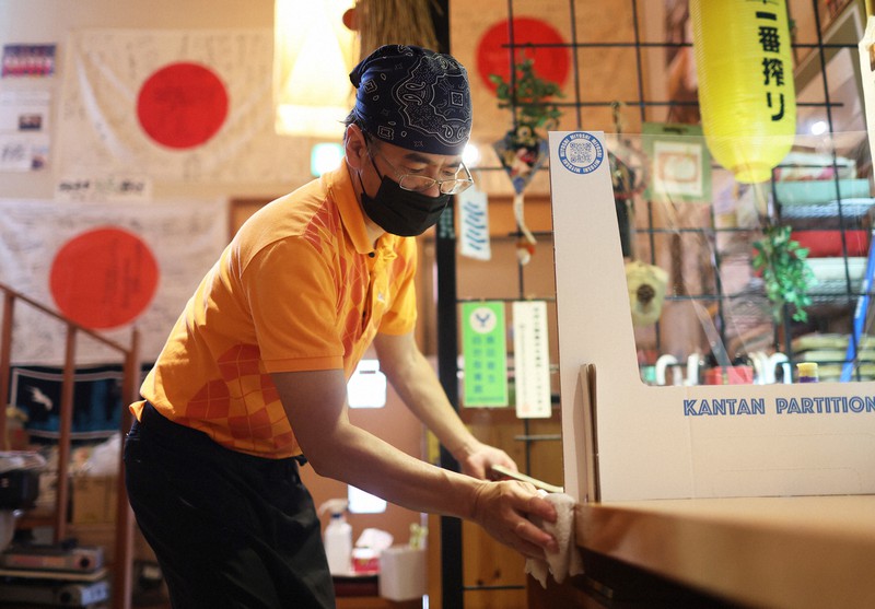 ランチタイムを終え、テーブルを拭く越前由記久さん。店内には選手のサインや寄せ書きされた日の丸が飾られている=東京都板橋区で2021年8月6日午後2時28分、小川昌宏撮影