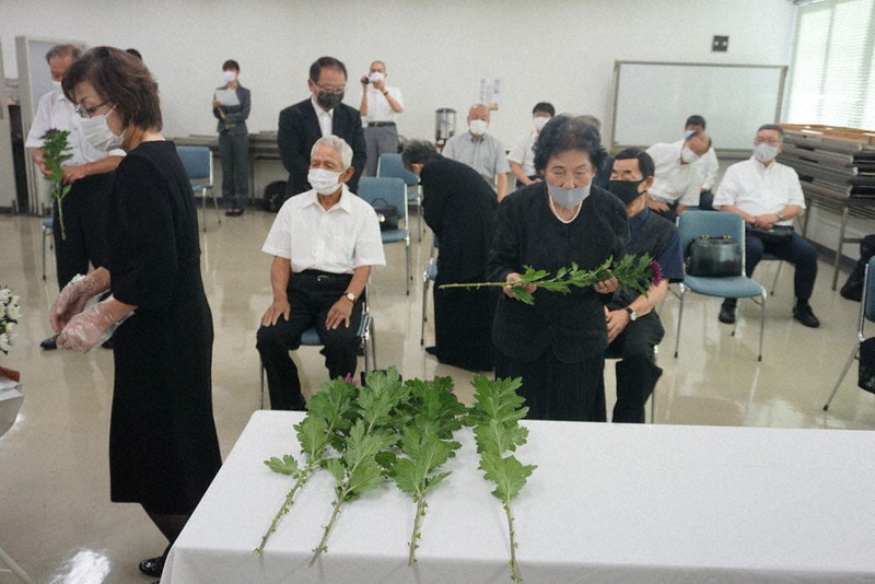 ゆだ苑での慰霊式で献花台に菊を手向ける参列者