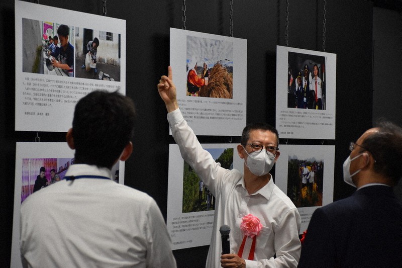 写真の説明をする崔領事(中央)ら