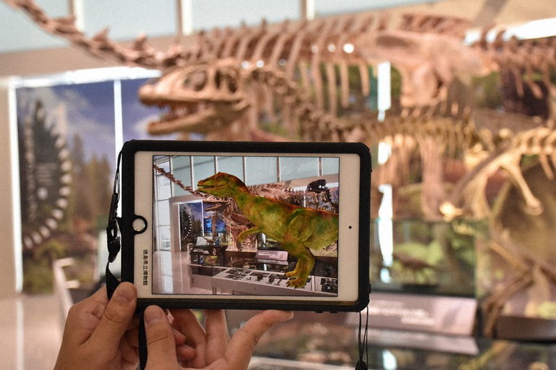 恐竜の骨格模型。スマートフォン上に、AR技術で再現された恐竜が映し出される=徳島市八万町の県立博物館で2021年8月7日午後2時16分、岩本桜撮影