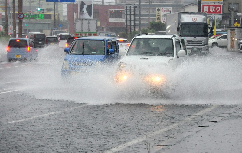 大雨で冠水した道路を水しぶきを上げて走る車=大分市で2021年8月12日午後0時49分、石井尚撮影