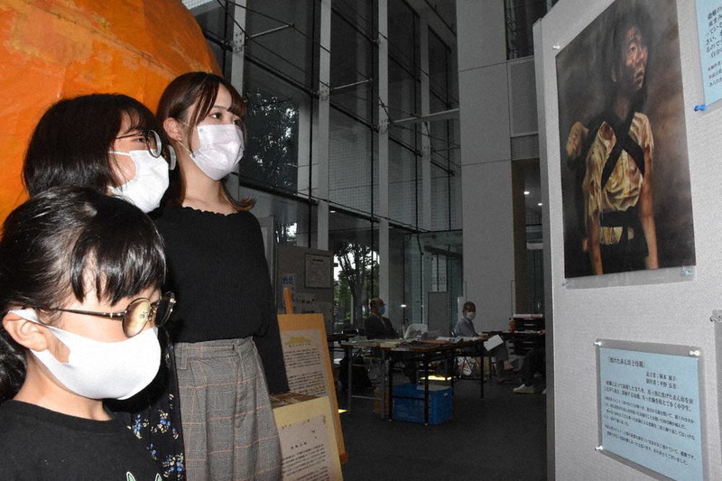 広島の高校生が描いた原爆の絵を見る銘苅旺(ひかる)さん(奥)ら=福島市で2021年8月13日、肥沼直寛撮影
