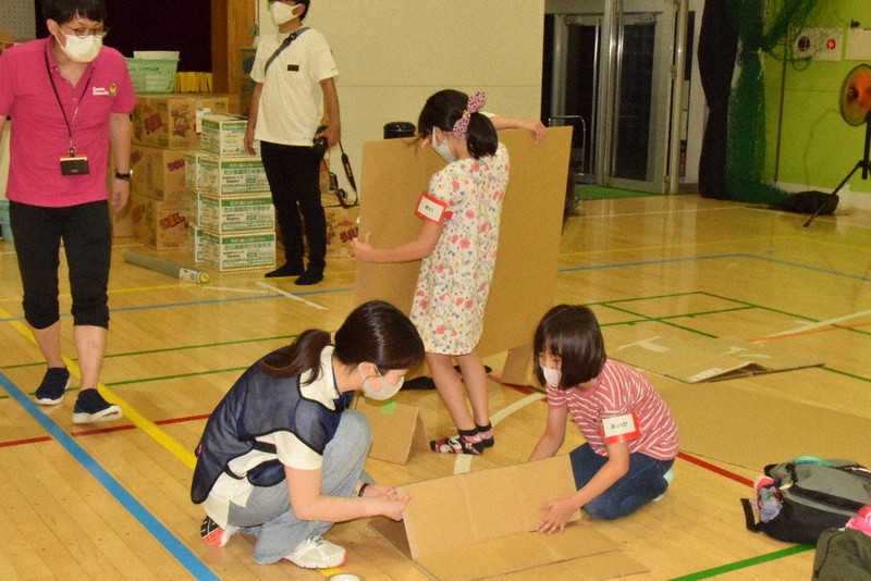 金井昌信教授(左)が見守る中、段ボールで寝床作りをする小学生ら=群馬県玉村町の町立中央小で2021年7月31日、大澤孝二撮影