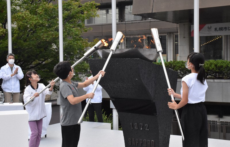 札幌市役所前の聖火台に火をともす子どもたち=札幌市中央区で2021年8月12日、土谷純一撮影