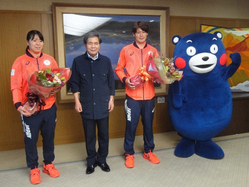 蒲島知事(左から2人目)から花束を受け取り、笑顔を浮かべる永田選手(左端)と岩下選手=熊本市の熊本県庁で2021年8月17日午前11時32分、山本泰久撮影