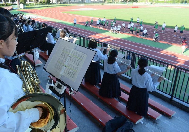 陸上競技場のトラックに立つアイルランドの選手らに向けて演奏する公津の杜中の吹奏楽部員=千葉県成田市中台の中台運動公園で2021年8月18日午後4時51分、中村宰和撮影