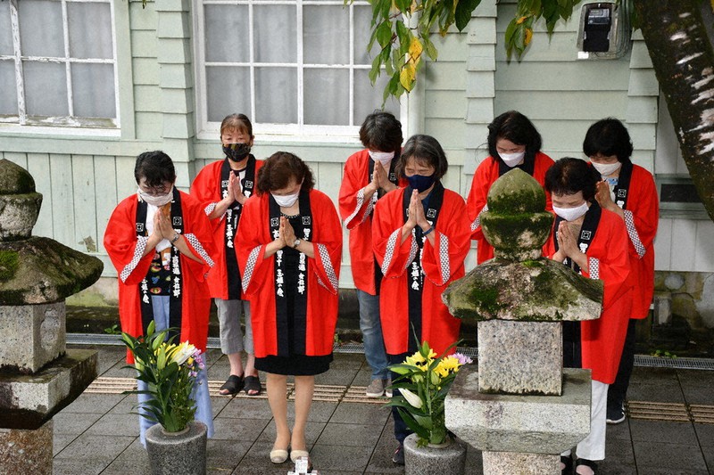 墓前で手を合わす「おかみさん」たち=高知県四万十市中村新町で、上野力撮影