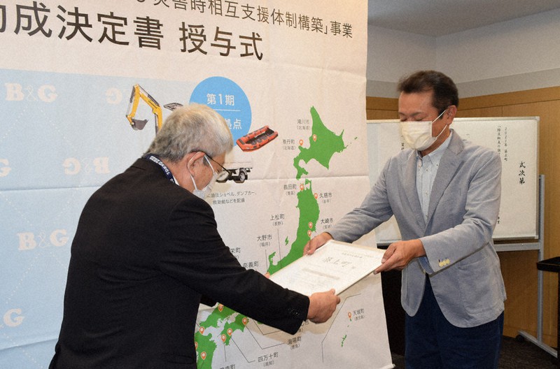 B&Gの菅原理事長(右)から決定書を受け取る新川久三町長