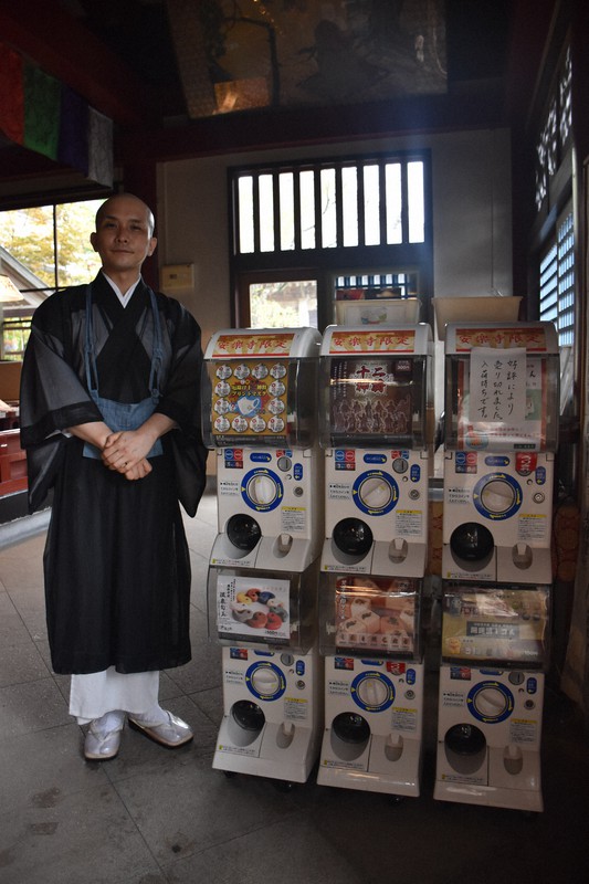 安楽寺に設置されたカプセル自動販売機と副住職の畠田裕峰さん=上板町引野で2021年8月18日午後2時14分、岩本桜撮影