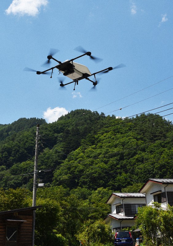 牛丼の箱を胴体に収容し、川池地区の広場に着地する運搬専用ドローン=山梨県小菅村で2021年7月21日午後0時39分、山本悟撮影