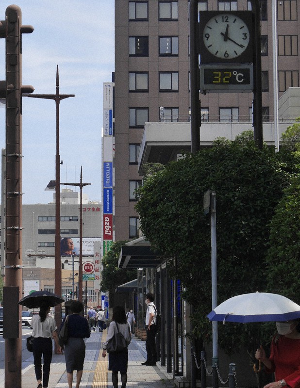 「32度」を示した静岡市内の温度計。暑さをしのぐため、日傘を差す人たちの姿が目立った=静岡市葵区で2021年8月26日午後0時20分、水戸健一撮影