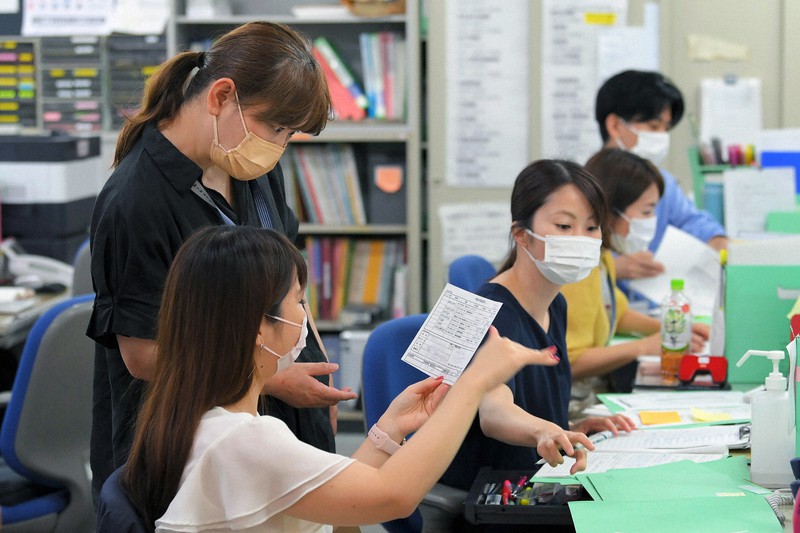 新型コロナウイルスの陽性者に電話連絡しながら、対応について話し合う保健師や看護師ら=東京都港区のみなと保健所で2021年8月5日午前10時24分、手塚耕一郎撮影(画像の一部を加工しています)