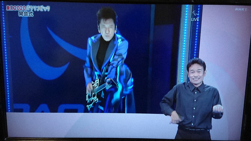 パラリンピック開会式で布袋寅泰さんの熱演(画面)を伝える、ろう通訳=NHKEテレから