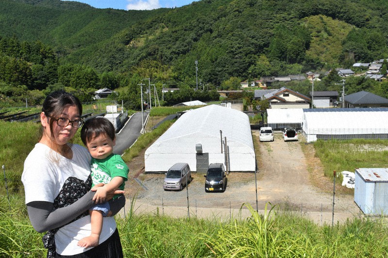 災害現場跡に立つ中原真耶さんと長男向葵ちゃん。下のハウス付近に自宅があった=和歌山県田辺市伏菟野で、竹内之浩撮影