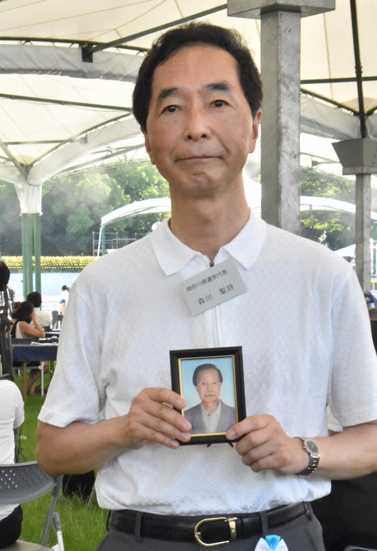 神奈川県の遺族代表として平和記念式典に参列した森川聖詩さん。手に持つ写真は、被爆者の父定實さん=広島市中区の平和記念公園で2021年8月6日午前7時42分、小山美砂撮影