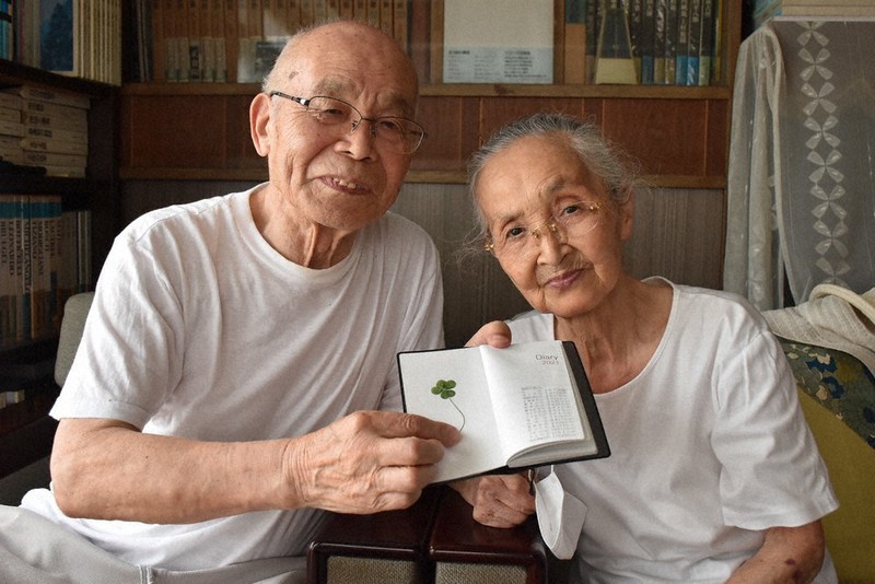 五つ葉のクローバーを手に笑顔を見せる荒井満さん(左)とシゲ子さん夫妻=宇都宮市鶴田町で2021年8月24日、鴨田玲奈撮影