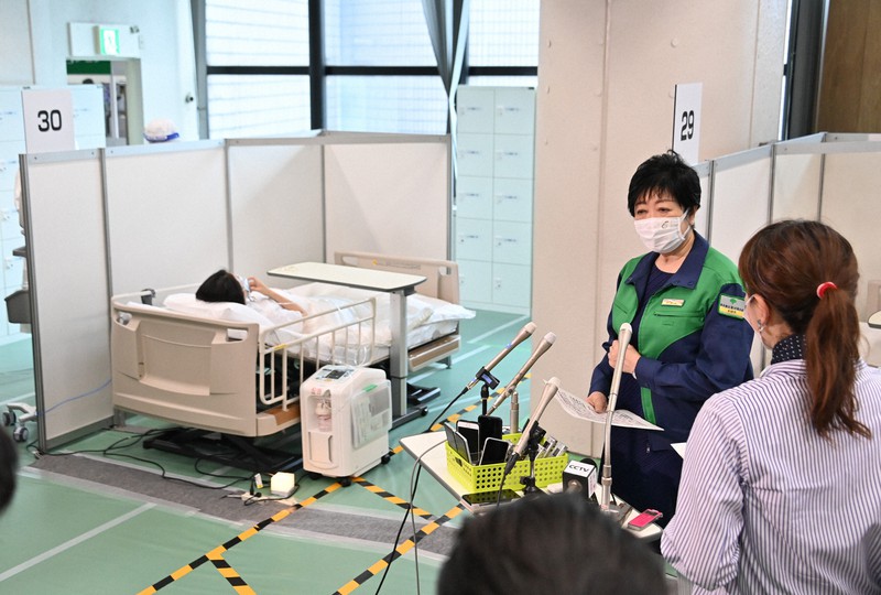 自宅療養者のうち酸素投与が必要となった人のための「酸素投与ステーション」を視察後、取材に応じる東京都の小池百合子知事(右奥)=東京都渋谷区で2021年8月21日、宮間俊樹撮影