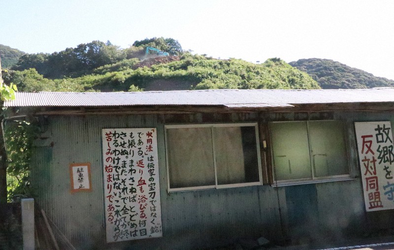 石木ダムの本体部分となる山を掘削するパワーショベル(中央奥)と水没予定地の住民が建てた団結小屋=長崎県川棚町で2021年9月8日午後3時20分、綿貫洋撮影
