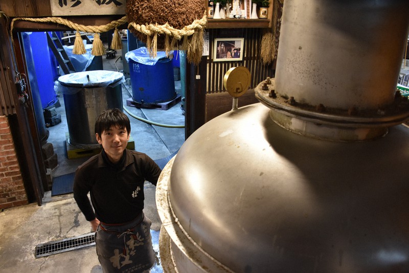 ジンを造る蒸留器。奥は日本酒の酒蔵=長崎県佐世保市城間町の梅ケ枝酒造で2020年4月9日午後3時31分、今野悠貴撮影