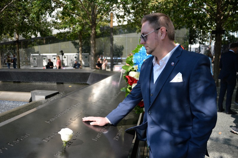 世界貿易センター(WTC)跡地の慰霊モニュメントの前で、プレートに刻まれた母親のドナ・ジョルダーノさんの名前に触れるマイケル・ジョルダーノさん=米ニューヨークで2021年9月10日、隅俊之撮影