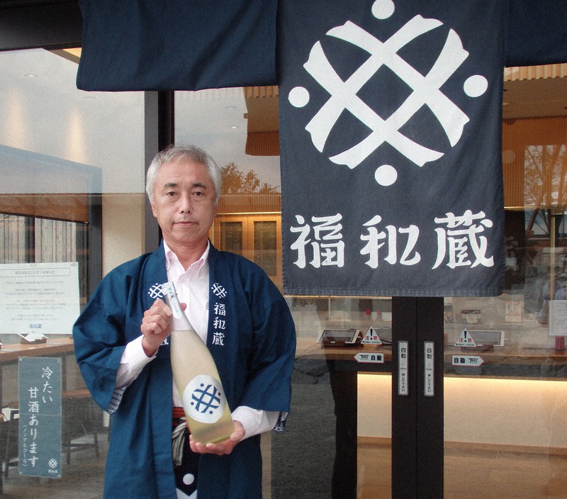 店舗前で新商品の「福和蔵」(純米吟醸)を持つ井村屋の濱口昭弘・新価値創造カンパニー長=三重県多気町で2021年9月1日、森有正撮影