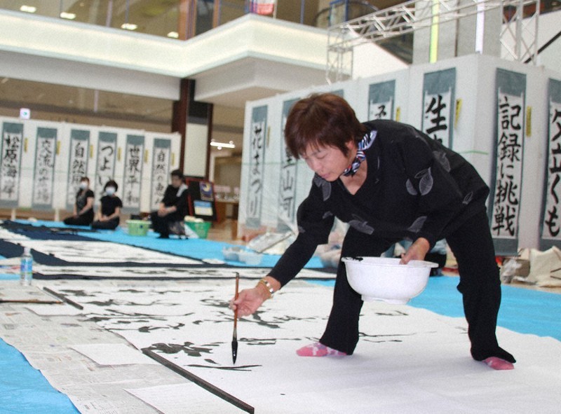 席上揮毫のリハーサルで、アニメ映画「鬼滅(きめつ)の刃(やいば)」の主題歌「炎(ほむら)」の歌詞を書く青柳吟風さん=福井県越前市新町のシピィで