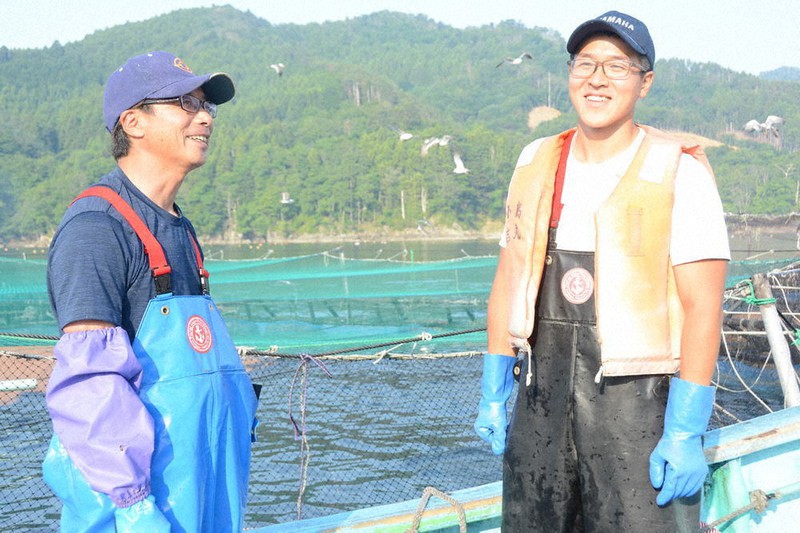 ギンザケのいけすの前で語り合う三浦大輝さん(右)と佐藤一さん=宮城県石巻市雄勝町で6月