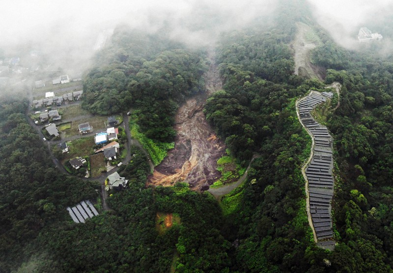 宅地や太陽光発電所にはさまれた土石流の起点とみられる現場(中央)。土砂は写真の上方向に向かって流れた=静岡県熱海市伊豆山で2021年7月3日午後5時50分、本社ヘリから竹内紀臣撮影