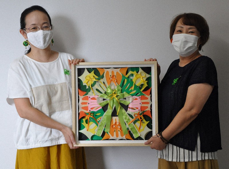 シトラスリボンをテーマにした作品を手にする橋本順子さん(右)と宇野裕美さん。胸に付けているのは橋本さんが手作りしたリボン=近江八幡市役所で2021年9月16日午後1時42分、村瀬優子撮影