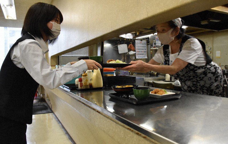 寿子さん(右)から笑顔で料理を受け取る女性行員