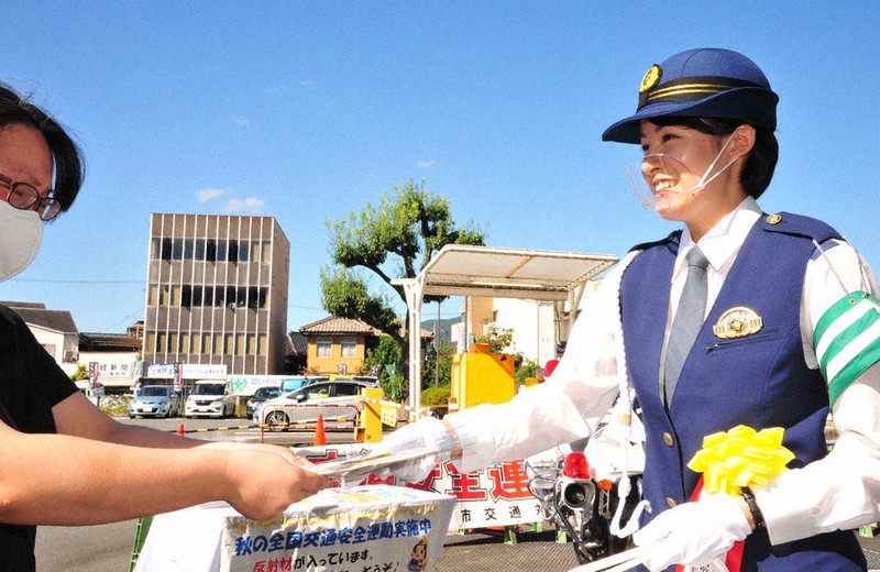 市民に啓発グッズを渡し交通安全を呼びかける一日警察署長の叶羽時さん(右)=京都府福知山市内記の市役所前で、佐藤孝治撮影