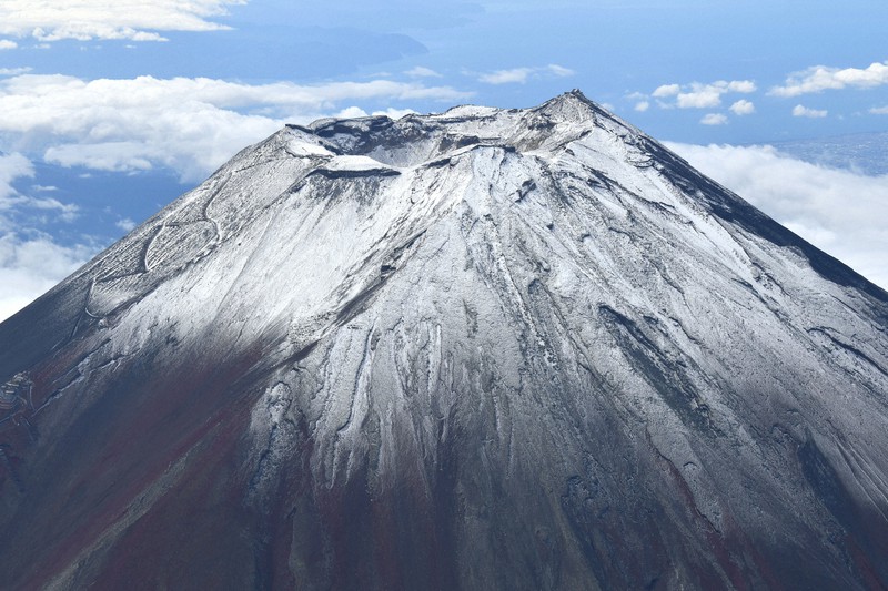 いったんは「初冠雪」と発表された富士山。記録の取り直しは例がないという=2021年9月7日午前9時44分、本社ヘリから丸山博撮影