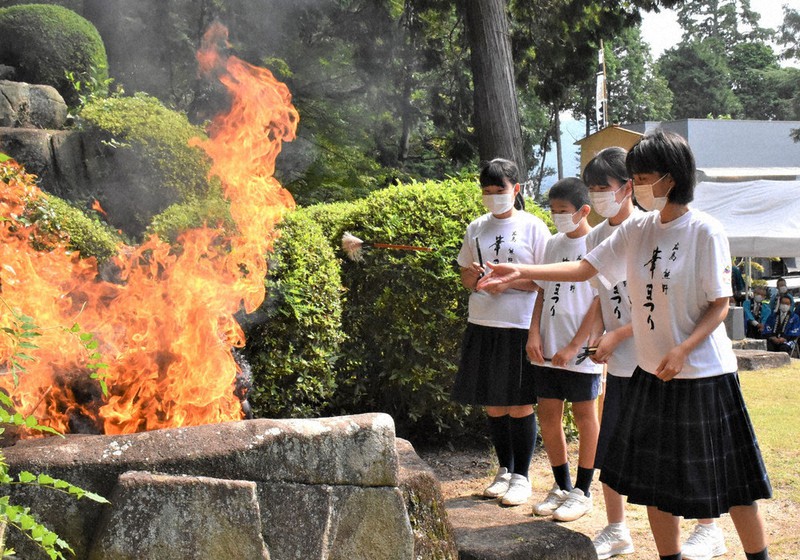 使い終わった筆を浄火へ投じる子どもたち=広島県熊野町中溝5の榊山神社で、根本佳奈撮影