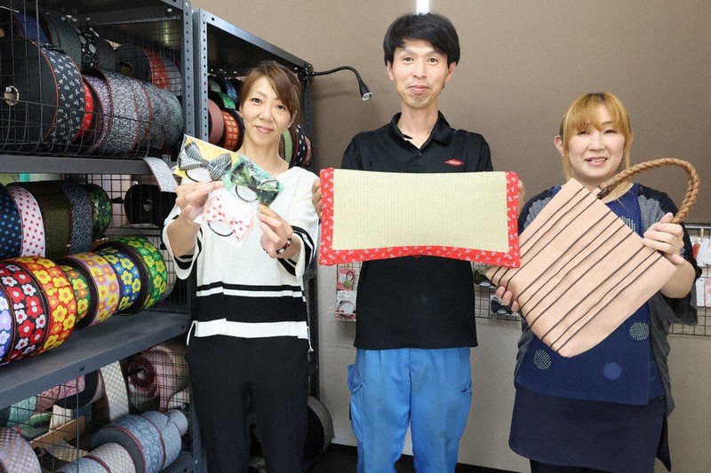 畳縁で作った商品を持つ香良昌宏社長(中央)ら。左端に色とりどりの畳縁が並ぶ。=丹波市山南町和田の横谷で2021年7月20日午後2時53分、幸長由子撮影
