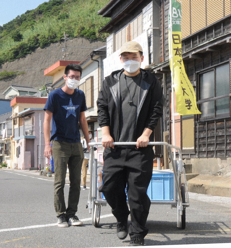 食料を載せたリヤカーを引く日本文理大の学生