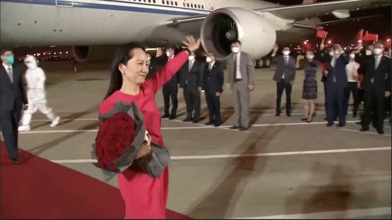 中国に帰国し、飛行機から降りて手を振る華為技術(ファーウェイ)の孟晩舟副会長=中国広東省深圳の空港で2021年9月25日、中国中央テレビ・ロイター