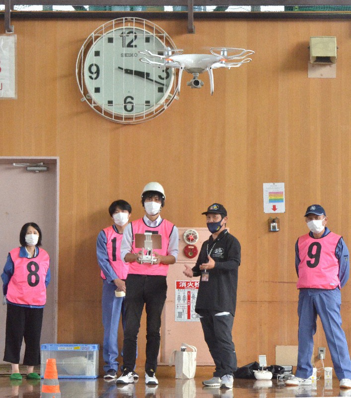 ヘルメットをかぶり、送信機を手にドローンを操縦する職員=下茨城県妻市唐崎で2021年9月22日、安味伸一撮影
