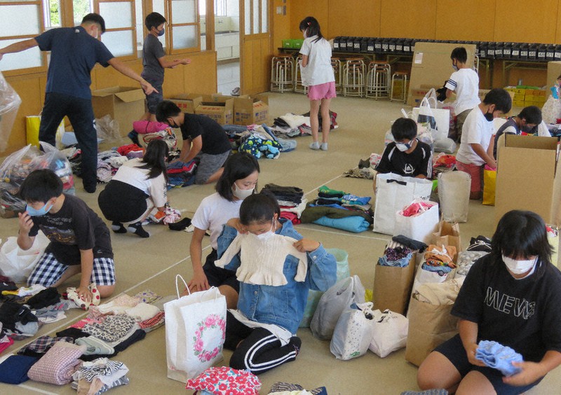 地域の人たちから寄せられた子ども服を丁寧に仕分けをする児童たち=愛知県岡崎市稲熊町の市立梅園小で2021年9月27日、渡辺隆文撮影