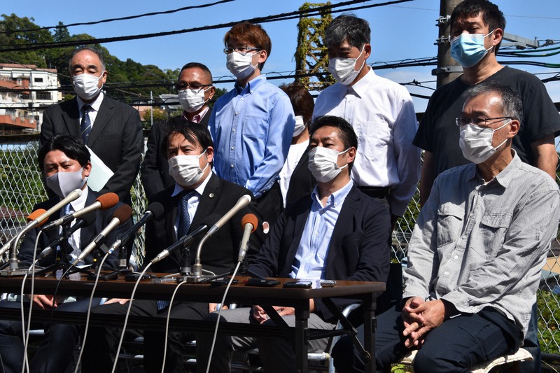 訴状の提出後、被災現場近くで記者会見に臨む加藤博太郎弁護団長(前列左から2番目)と「熱海市盛り土流出事故被害者の会」の瀬下雄史会長(前列右から2番目)ら原告団=熱海市伊豆山で2021年9月28日午後0時10分、深野麟之介撮影