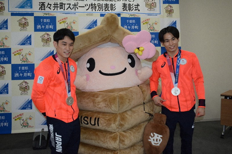 町のマスコットキャラクター「井戸っこ(しすいちゃん)」の前で記念撮影に応じる萱和磨選手(右)と谷川航選手=千葉県酒々井町役場で2021年9月30日、中村宰和撮影