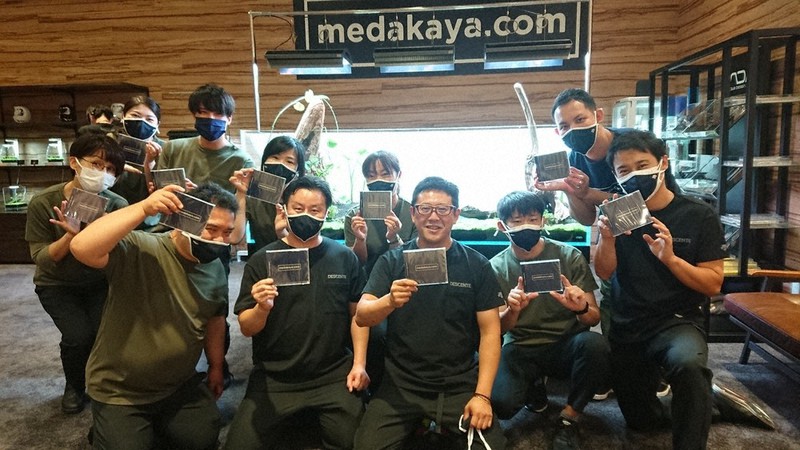 発売されたCD「めだか達への伝言」を掲げる青木さん（前列中央）と障害者就労支援事業所の利用者、スタッフら仲間たち＝八王子市旭町で2021年10月1日、野倉恵撮影