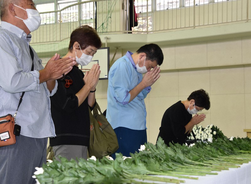 献花台の前で祈りをささげる参列客=静岡県熱海市の伊豆山小学校で2021年10月10日午前10時48分、深野麟之介撮影