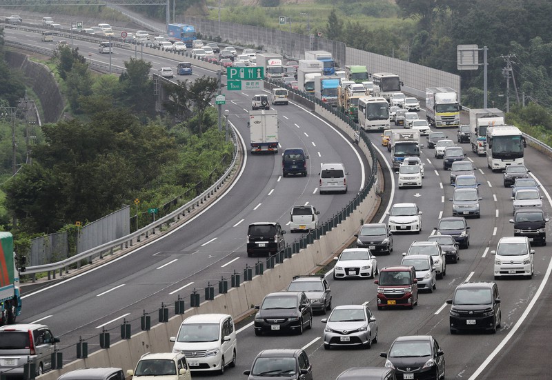 お盆休みに古里や行楽地へ向かう車などで渋滞する東名阪自動車道の下り線(右、写真奥が名古屋方面)=三重県四日市市で2017年8月、兵藤公治撮影